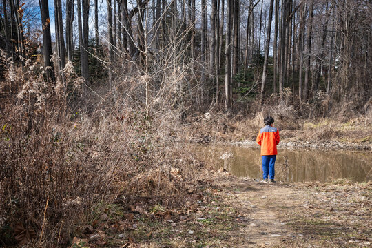 Young boy fishing from shore of lake in winter.