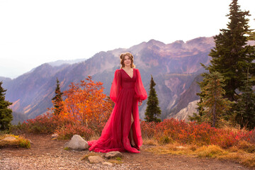 Smiling woman in red gown standing in front of mountain