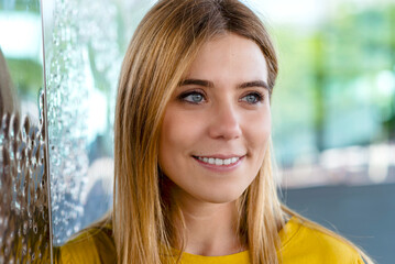 young woman's captivating gaze with a warm smile, wearing a yellow top