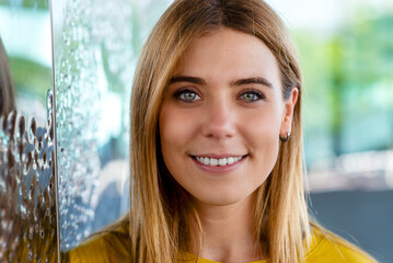 young woman's captivating gaze with a warm smile, wearing a yellow top