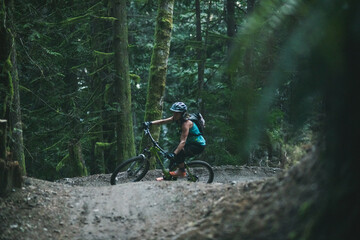Woman riding mountain bike on trail in the forest