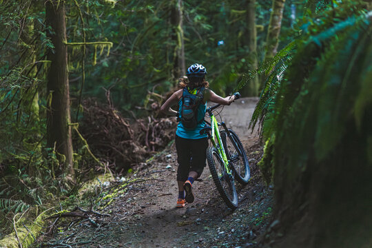 Woman pushing mountain bike on trail in the forest