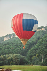 Naklejka premium A big balloon in flight. Mountainous terrain. Evening time of the day