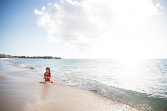 Wide Angle of Young Girl Playing With Sand at Edge of Caribbean Sea