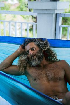 Arabic palestinian man with long curly hair is resting in a hammock.