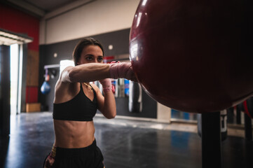 Fit female boxer training on punching bag in gym