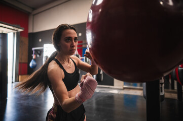 Determined woman training on punching bag in gym