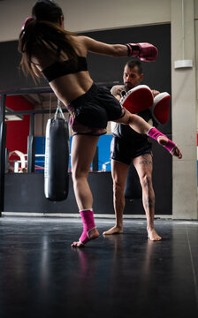 Female fighter practicing Muay Thai with trainer in boxing club
