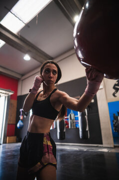 Determined female boxer exercising with punching bag at gym