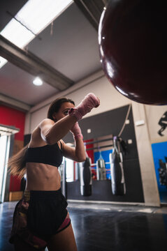 Fit sportswoman exercising with punching bag at gym