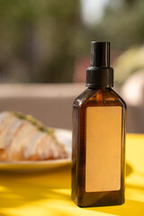 A bottle of brown cosmetics stands on the table against the background of food