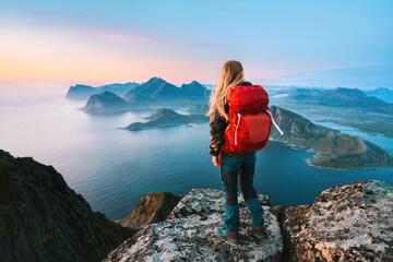 Woman mountaineering with backpack solo girl traveling in Lofoten islands enjoying aerial view...
