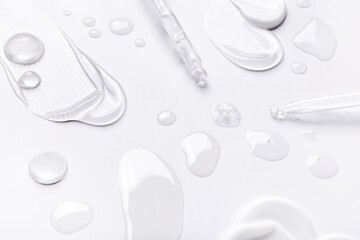 samples of cosmetic care products, smear of cream and gel texture drops of serum from a pipette drops of tonic oil on a light background