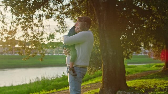 Dad and Son Enjoy a Day Together in a Park at Sunset.
Romantic moment between Father and Son with hugs, caresses and kisses.