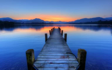 Poster wooden jetty extending into the serene waters of the Lake District, with distant mountains © hakule