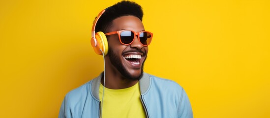 A man with a beard and sunglasses is smiling while wearing headphones, his facial hair and eyewear complementing his happy expression