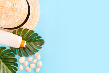 Summer holidays with seashells, palm leaves and straw hat. Blue background with copy space. Top...