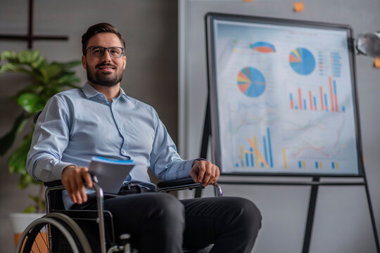 Disabled male business manager in wheelchair giving presentation at meeting on chartboard
