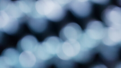 Blurred white Bokeh of light on black background in vintage tone. Green lighting blurry wallpaper.