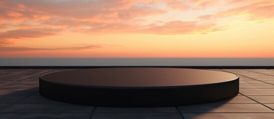 A black podium stands on a tiled floor against the backdrop of the ocean at sunset, with a red sky at dusk and the horizon blending with the natural landscape