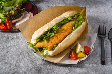 Fried fish sandwich with greens on the stone table. Turkish name Balik Ekmek