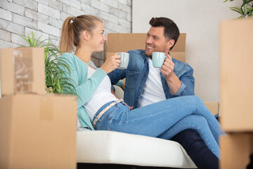 young couple sitting back relaxing while moving in new home - Powered by Adobe