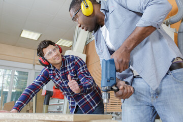 apprentice and teacher drilling wooden plank together