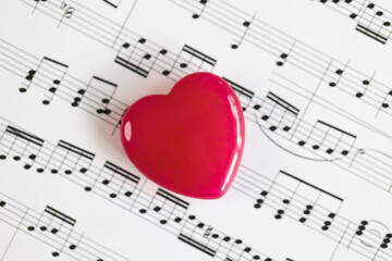 Red heart on paper with musical notes close-up.