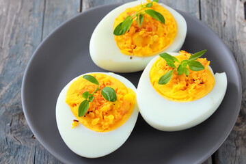 stuffed eggs. three boiled egg halves with herbs lie on a gray plate, top view, close-up, snack concept