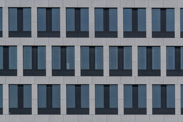 Detail of the facade of modern office building with grey windows and a symmetrical effect.