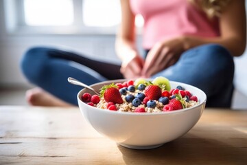 Athletic woman eating a healthy bowl of muesli with fruit in the kitchen