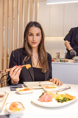 Beautiful young woman eating sushi - 769498023