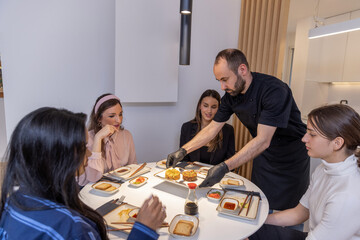 Group of people having dinner with private chef at home