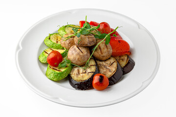 Grilled vegetables: peppers, mushrooms, zucchini on a white plate. Banquet festive dishes. Gourmet restaurant menu. White background.