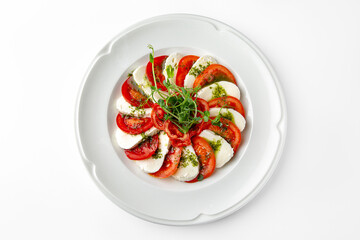Caprese, a dish of tomatoes, mozzarella and pesto on a white plate. Banquet festive dishes. Gourmet...