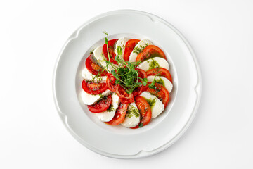 Caprese, a dish of tomatoes, mozzarella and pesto on a white plate. Banquet festive dishes. Gourmet restaurant menu. White background.