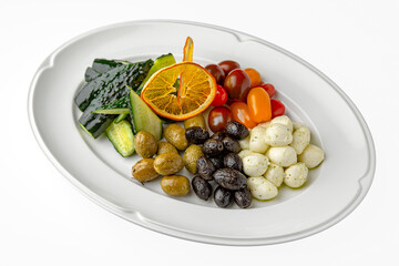 Marinated cheese, olives, tomatoes on a white plate. Banquet festive dishes. Gourmet restaurant menu. White background.