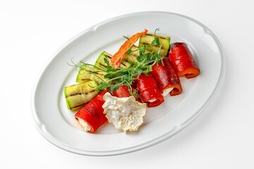 Zucchini and sweet pepper rolls with cheese on a white plate. Banquet festive dishes. Gourmet restaurant menu. White background.