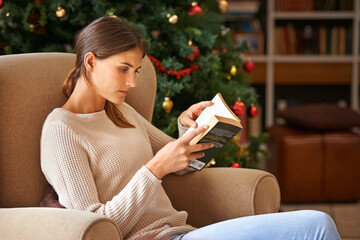 Woman, reading and book on sofa at christmas in home on vacation. Comfortable, female person and fantasy novel for learning or education in living room during festive holiday with decoration