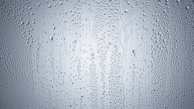 water drops following down the surface of glass. Drops of Rain trickling down.