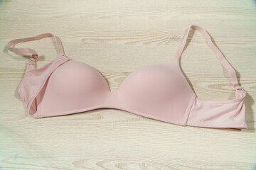 A woman's bra on a light wood background. View from above.