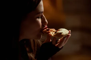 Deurstickers Beautiful girl with red lipstick eats pepperoni pizza in a pizzeria © dvoinik