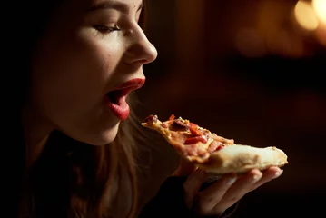 Selbstklebende Fototapeten Girl with red lipstick sexy eating pizza in a pizzeria © dvoinik