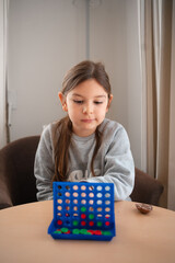 A focused child strategizing her next move in a tabletop game, embodying concentration and playful...