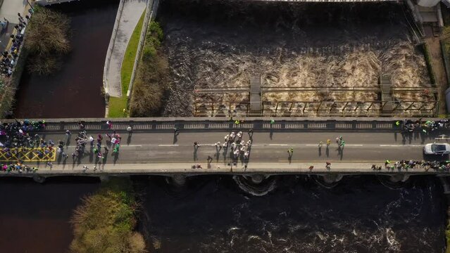 St. patrick's day parade crossing Salmon weir bridge in galway city, aerial view