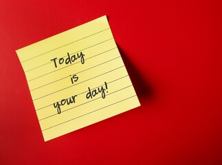 Yellow note on red copy space background with handwriting - TODAY IS YOUR DAY - positive self talk...