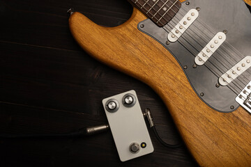 Electric guitar and a guitar pedal on wooden floor