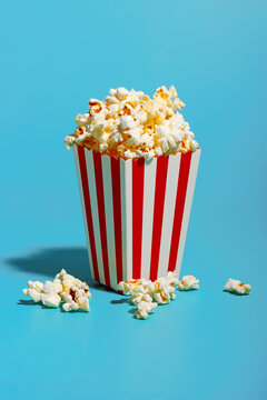 Popcorn in red striped container over blue background