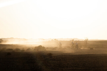 Cyclists cyling on a dusty and foggy Sahara desert in Morocco