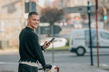 young man walking on the street with bicycle and mobile phone